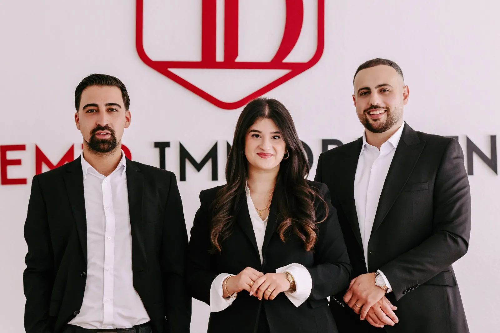 Semih Coskun, Ayse Demir und Deniz Demir vor der Logowand im Büro in Bremen-Vegesack